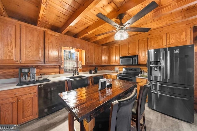 kitchen with brown cabinetry, light wood-style floors, beamed ceiling, and black appliances