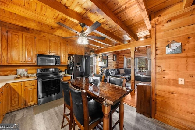 kitchen featuring light countertops, stainless steel microwave, black refrigerator with ice dispenser, electric range, and open floor plan