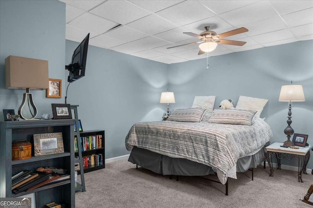 bedroom with ceiling fan, a drop ceiling, carpet, and baseboards