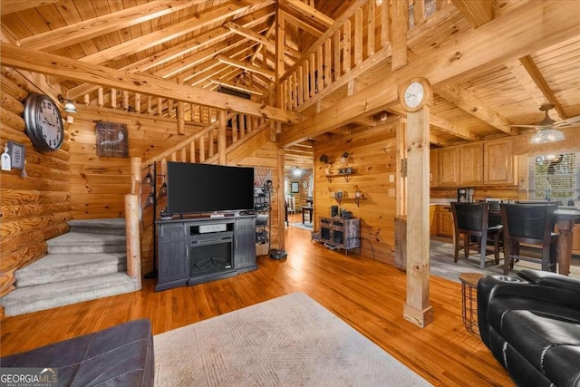 living area with wooden walls, wooden ceiling, light wood-style flooring, and beam ceiling