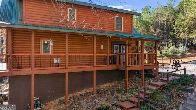 rear view of property featuring metal roof, a wooden deck, and log siding