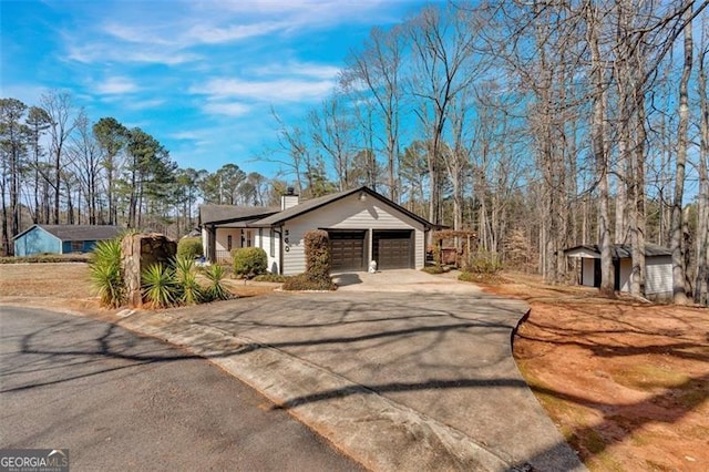 single story home with a garage, concrete driveway, and a chimney