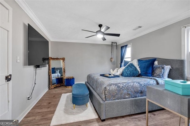 bedroom with ornamental molding, visible vents, and wood finished floors