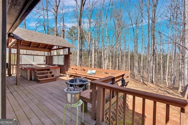 wooden terrace featuring a hot tub, a fire pit, and a gazebo