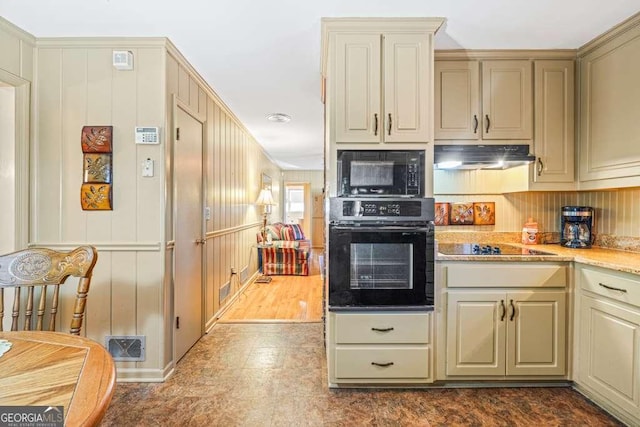 kitchen featuring black appliances, under cabinet range hood, visible vents, and cream cabinetry