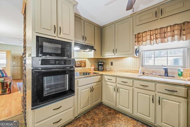 kitchen featuring a sink, cream cabinets, under cabinet range hood, and black appliances