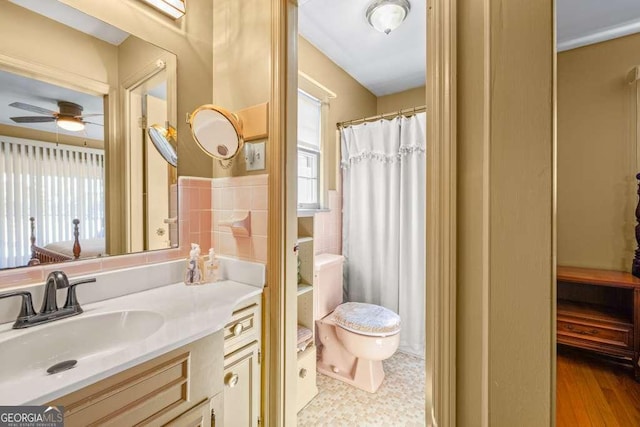 full bathroom featuring a ceiling fan, a shower with shower curtain, toilet, vanity, and tile walls