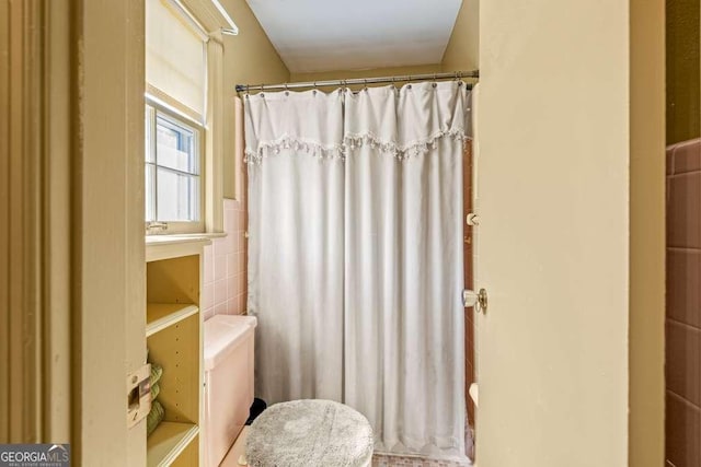 bathroom with a shower with shower curtain, tile walls, and toilet