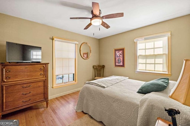 bedroom with baseboards, a ceiling fan, and light wood-style floors