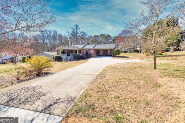 ranch-style house with concrete driveway, a porch, and a front yard