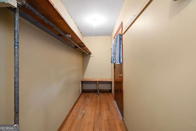 walk in closet with light wood-style floors