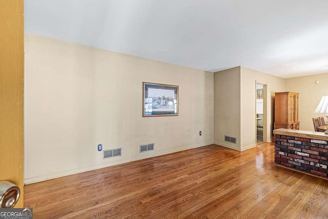 living area with wood finished floors, visible vents, and baseboards