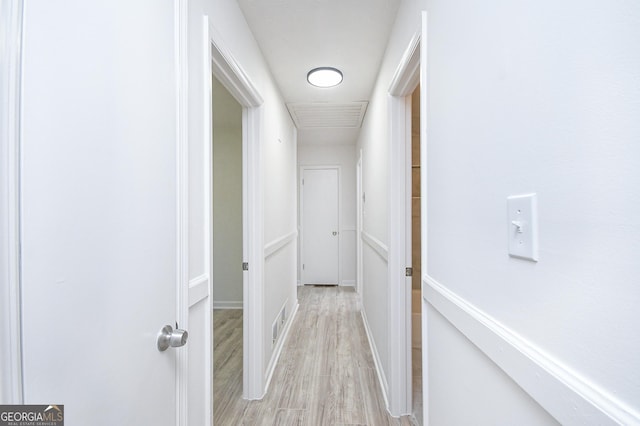 corridor with light wood-style flooring and baseboards