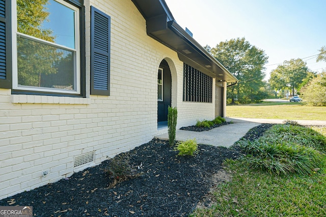 view of home's exterior with crawl space, a yard, and brick siding