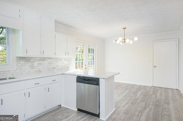 kitchen featuring light wood finished floors, white cabinets, light countertops, pendant lighting, and stainless steel dishwasher