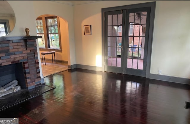 living room with visible vents, a fireplace, baseboards, and dark wood finished floors