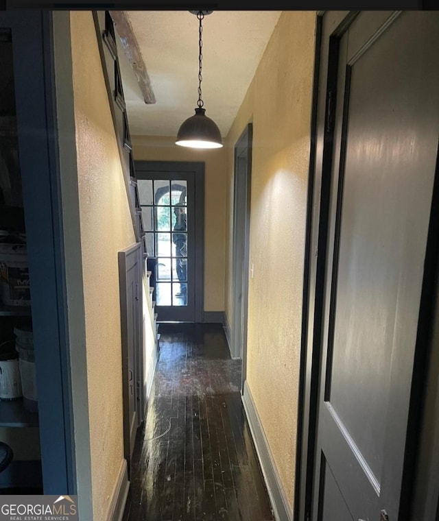 corridor with a textured wall, dark wood finished floors, and baseboards