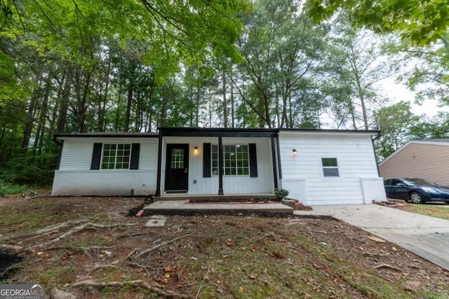 view of front of home featuring driveway, brick siding, and a porch