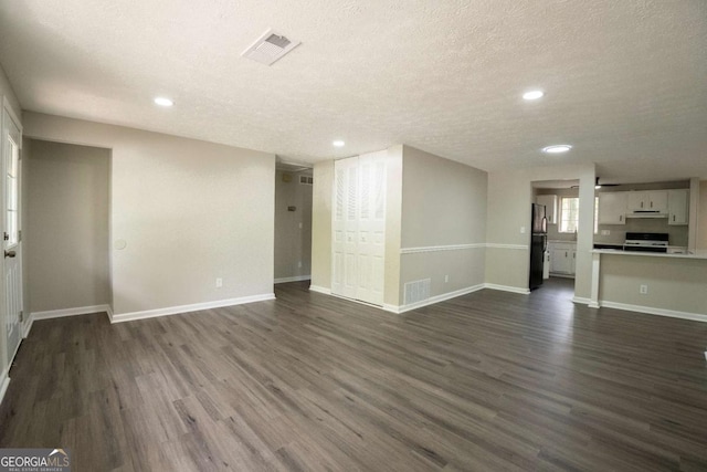 unfurnished living room featuring baseboards, visible vents, and dark wood-type flooring