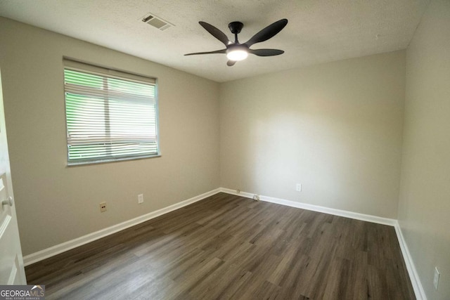 unfurnished room with baseboards, visible vents, a ceiling fan, dark wood-style floors, and a textured ceiling