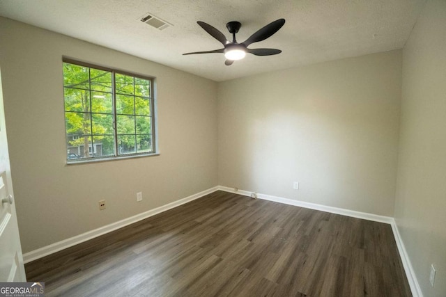 spare room featuring a ceiling fan, baseboards, visible vents, and dark wood-style flooring