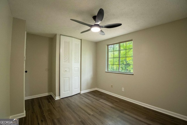 unfurnished bedroom featuring baseboards, a ceiling fan, dark wood-style flooring, a textured ceiling, and a closet