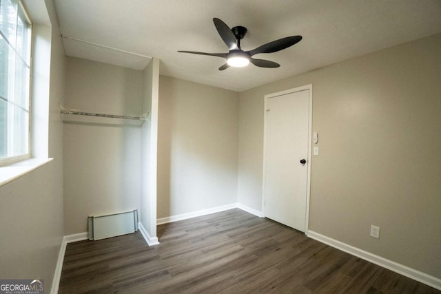 unfurnished bedroom featuring a ceiling fan, a closet, dark wood finished floors, and baseboards