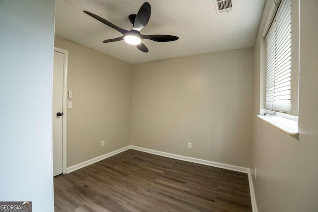 spare room with dark wood-style floors, baseboards, visible vents, and ceiling fan