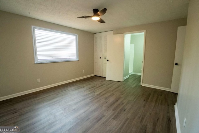 unfurnished bedroom with a closet, baseboards, dark wood finished floors, and a textured ceiling