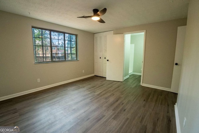 unfurnished bedroom featuring a textured ceiling, dark wood finished floors, a ceiling fan, and baseboards