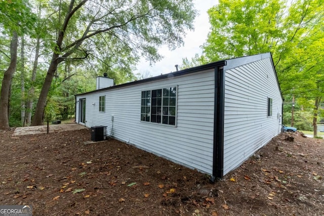 view of side of property featuring a chimney and central air condition unit