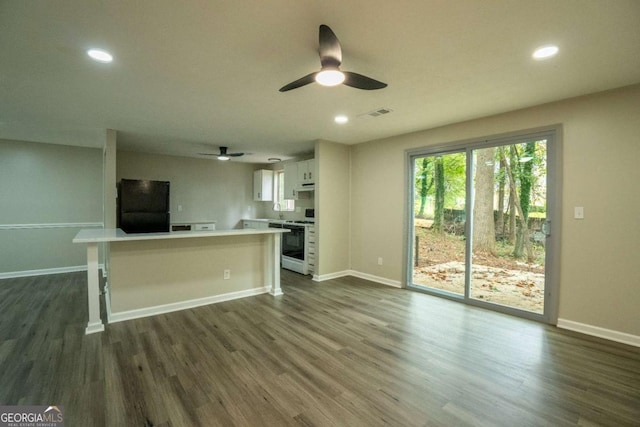 kitchen featuring dark wood-style flooring, white cabinets, light countertops, freestanding refrigerator, and white stove