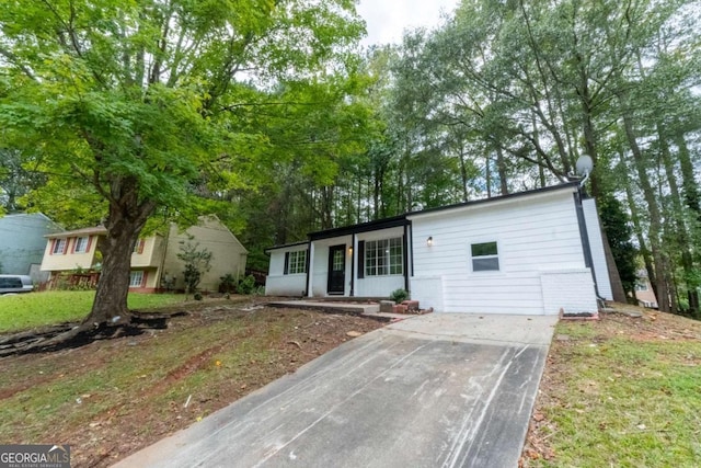 view of front of property featuring concrete driveway and a front lawn