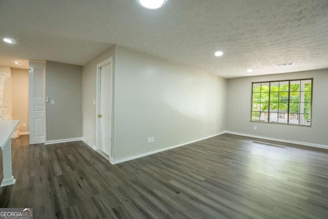 spare room featuring dark wood-style floors, recessed lighting, visible vents, a textured ceiling, and baseboards