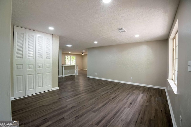 interior space featuring recessed lighting, visible vents, dark wood-type flooring, a textured ceiling, and baseboards