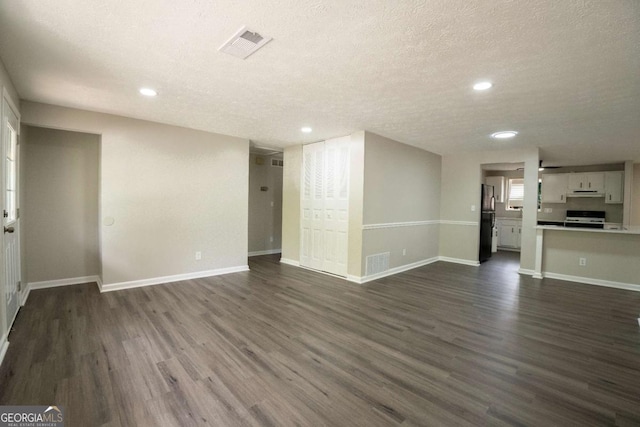 unfurnished living room featuring dark wood-type flooring, visible vents, and baseboards