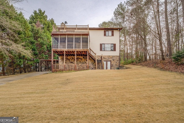 rear view of house with a chimney, a lawn, stairway, a sunroom, and stone siding