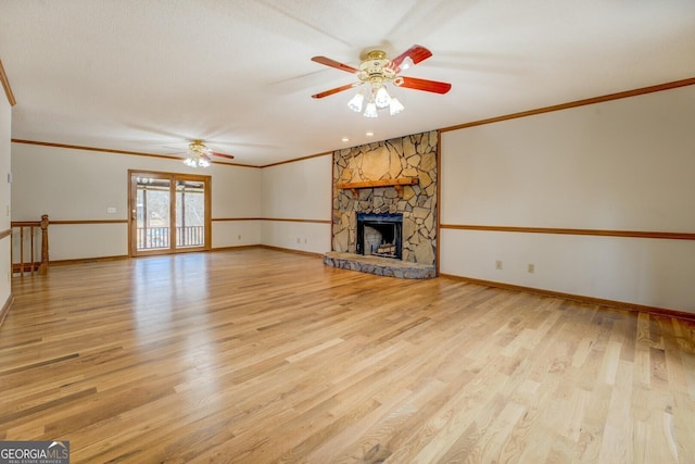 unfurnished living room with ornamental molding, a fireplace, light wood-style flooring, and a ceiling fan