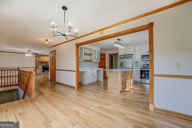 kitchen featuring stainless steel appliances, white cabinets, open floor plan, light countertops, and light wood-type flooring