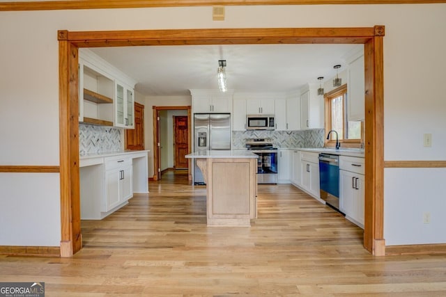 kitchen with appliances with stainless steel finishes, a center island, light countertops, light wood-type flooring, and white cabinetry