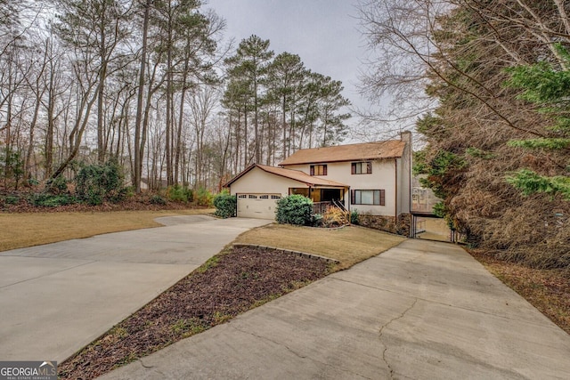 view of front of house with an attached garage, driveway, a gate, stucco siding, and a front yard