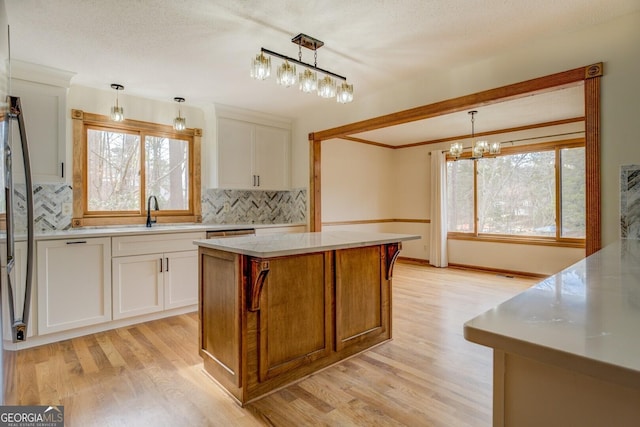 kitchen with light countertops, backsplash, a sink, and light wood-style floors