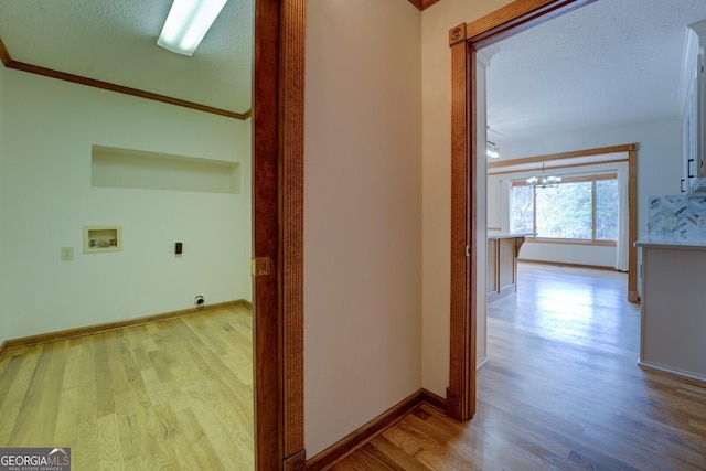 corridor with a chandelier, light wood-style flooring, baseboards, and a textured ceiling