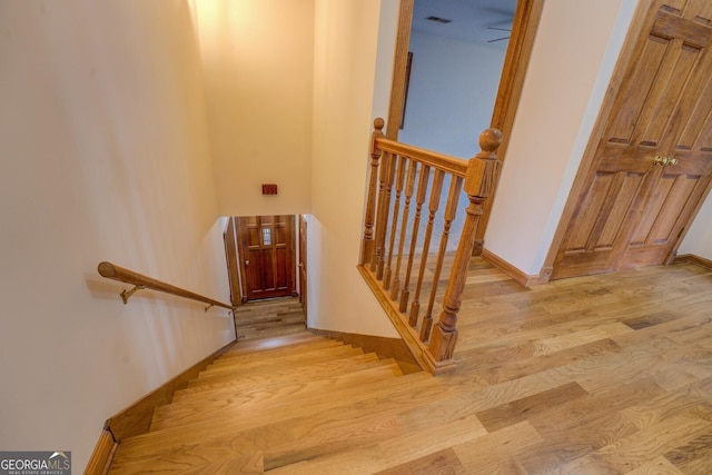 staircase with wood finished floors, visible vents, and baseboards