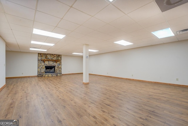 finished basement featuring a drop ceiling, a fireplace, wood finished floors, visible vents, and baseboards