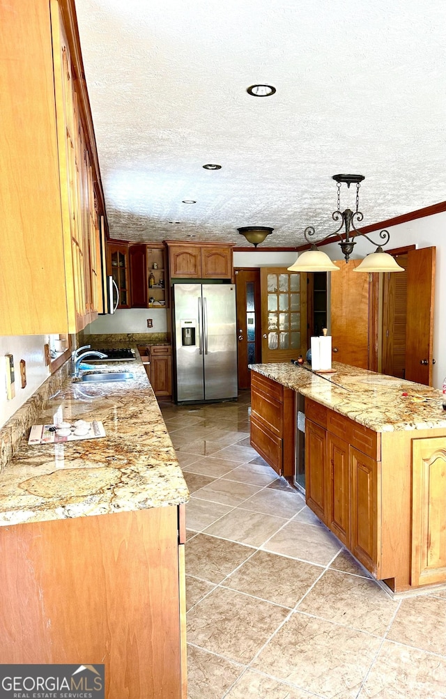 kitchen featuring stainless steel appliances, hanging light fixtures, brown cabinetry, and a sink