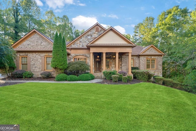 craftsman-style house featuring stone siding, brick siding, and a front yard