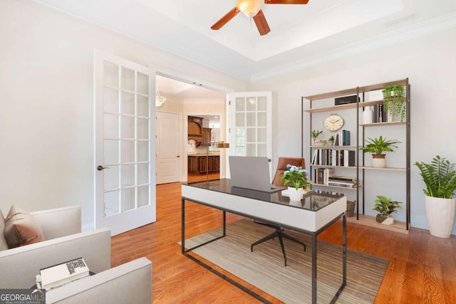 home office featuring a ceiling fan, a raised ceiling, wood finished floors, and french doors