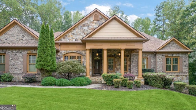 view of front of home with brick siding, a shingled roof, a standing seam roof, stone siding, and a front lawn