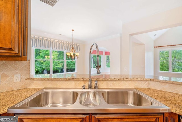 kitchen featuring decorative backsplash, visible vents, brown cabinetry, and a sink